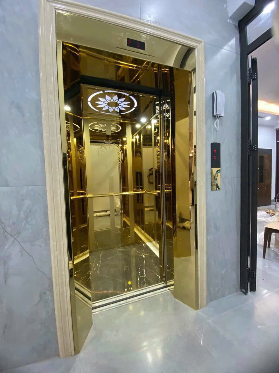 Thang máy gia đình vách kính mạ vàng sang trọng trong không gian nhà ở hiện đại